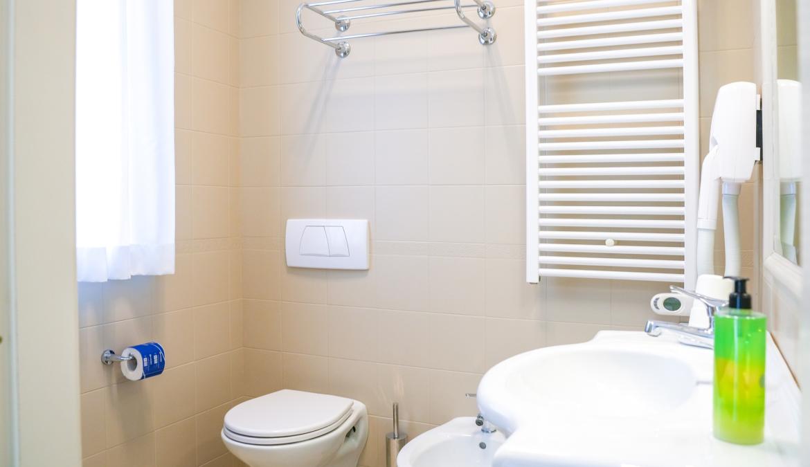 Bagno moderno con sanitari bianchi e portasciugamani.